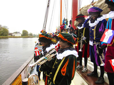 Pietenorkest staat te lachen en te zwaaien op de boot van Sinterklaas